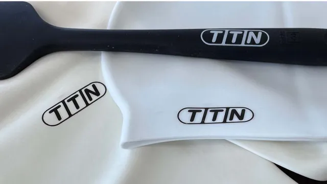 Automark AM-Si silicone pad printing ink prominently displayed on a black silicone spatula and white silicone swim caps, featuring the TTN logo, demonstrating excellent adhesion and flexibility.