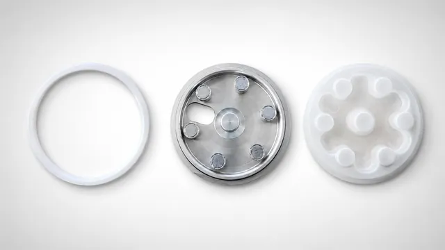 A disassembled view of an Automark pad printing ink cup liner system, showing a white ceramic ring, a stainless steel ink cup with magnetic posts, and a clear plastic liner, designed for quick and easy cleaning.