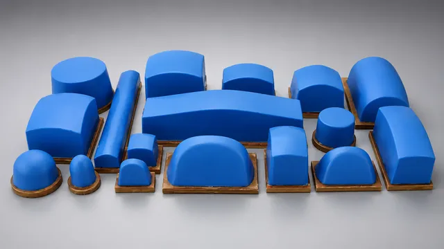 A wide array of blue pad printing pads of various shapes and sizes, arranged on a gray background, showcasing the diverse selection offered by Automark for different printing applications.
