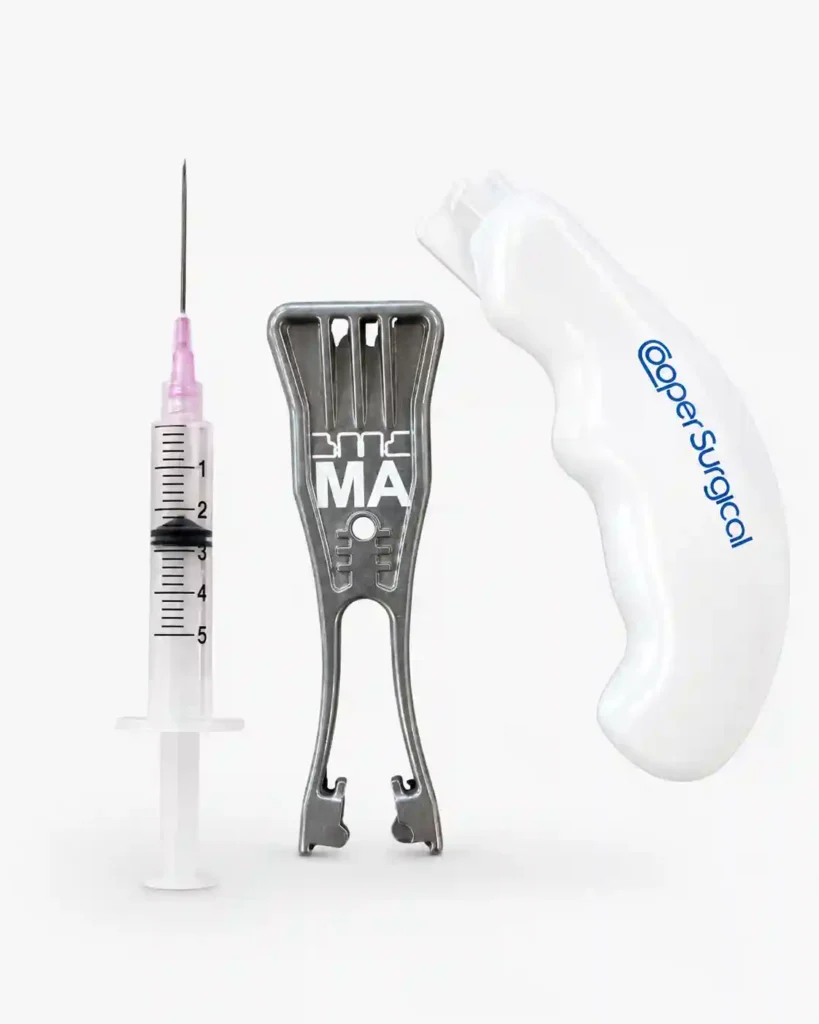 A collection of medical devices, including a syringe with a pink needle cap, a metallic surgical clip, and a white ergonomic surgical tool with the CooperSurgical logo, all featuring precise pad printing by Automark, against a clean white background.