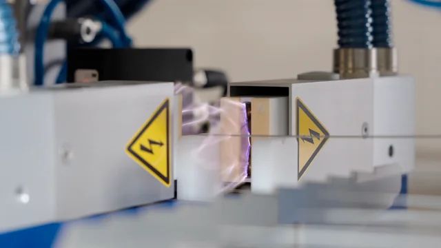 Close-up of a Corona treatment unit actively pre-treating catheter tubes for enhanced surface adhesion in a fully automated pad printing process by Automark, showing electrical discharge.