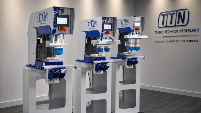 Three TTN Universal Series pad printing machines, 1-color and 2-color pad printers, displayed in a modern showroom, representing precision and performance from Automark.